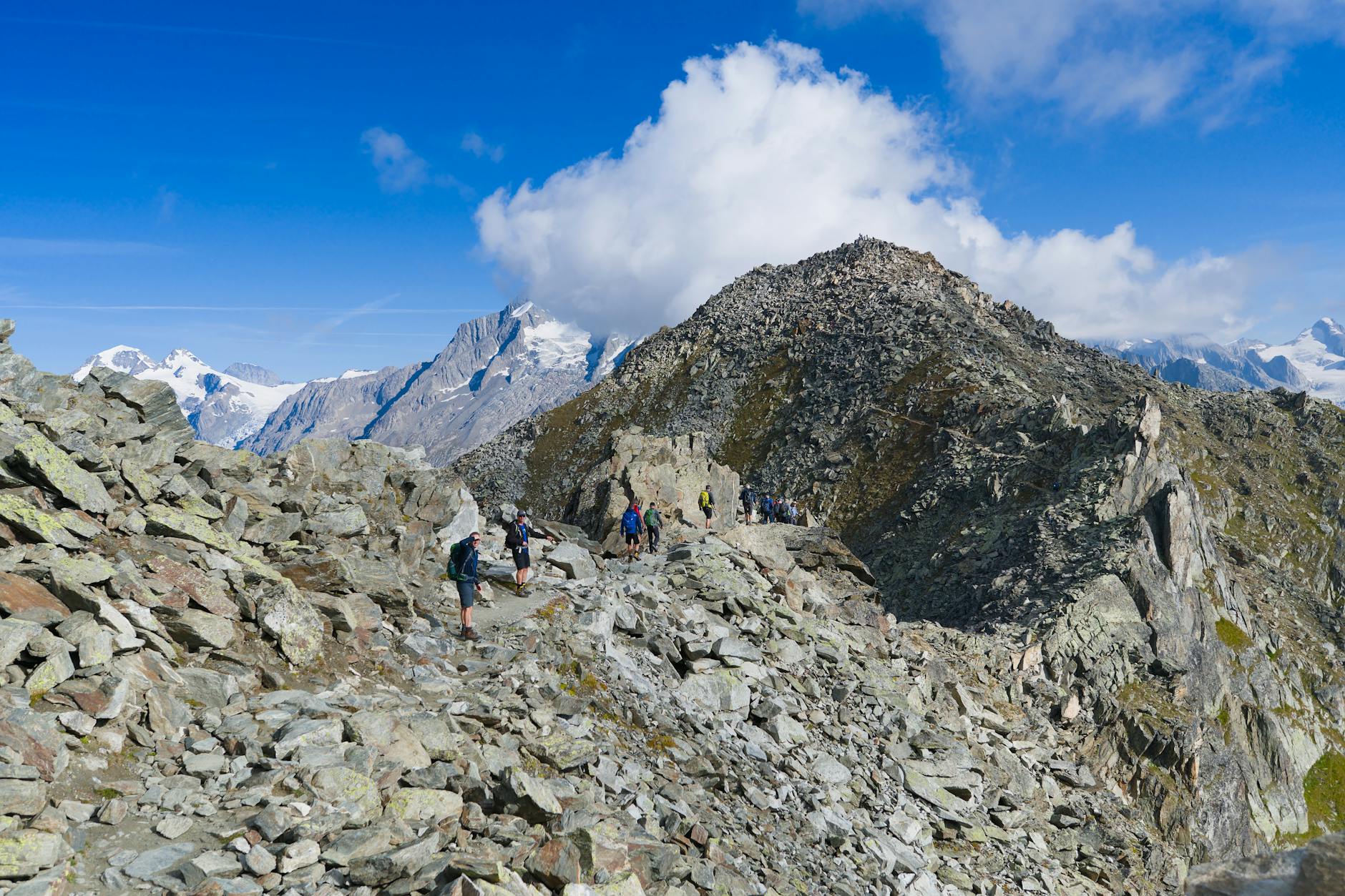Wędrowcy na skalistym szlaku w szwajcarskich Alpach w słoneczny dzień