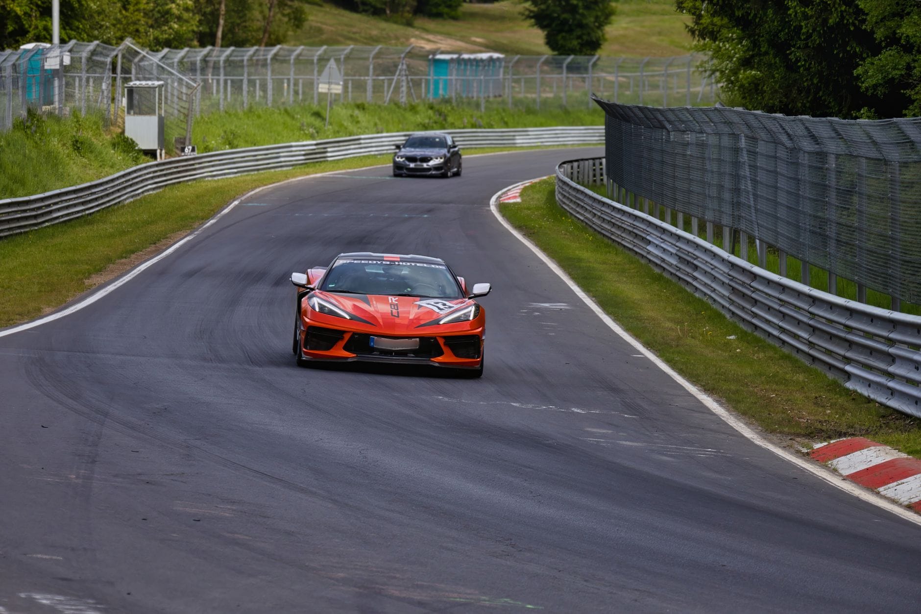 Ferrari pędzące po europejskim torze wyścigowym wśród zieleni