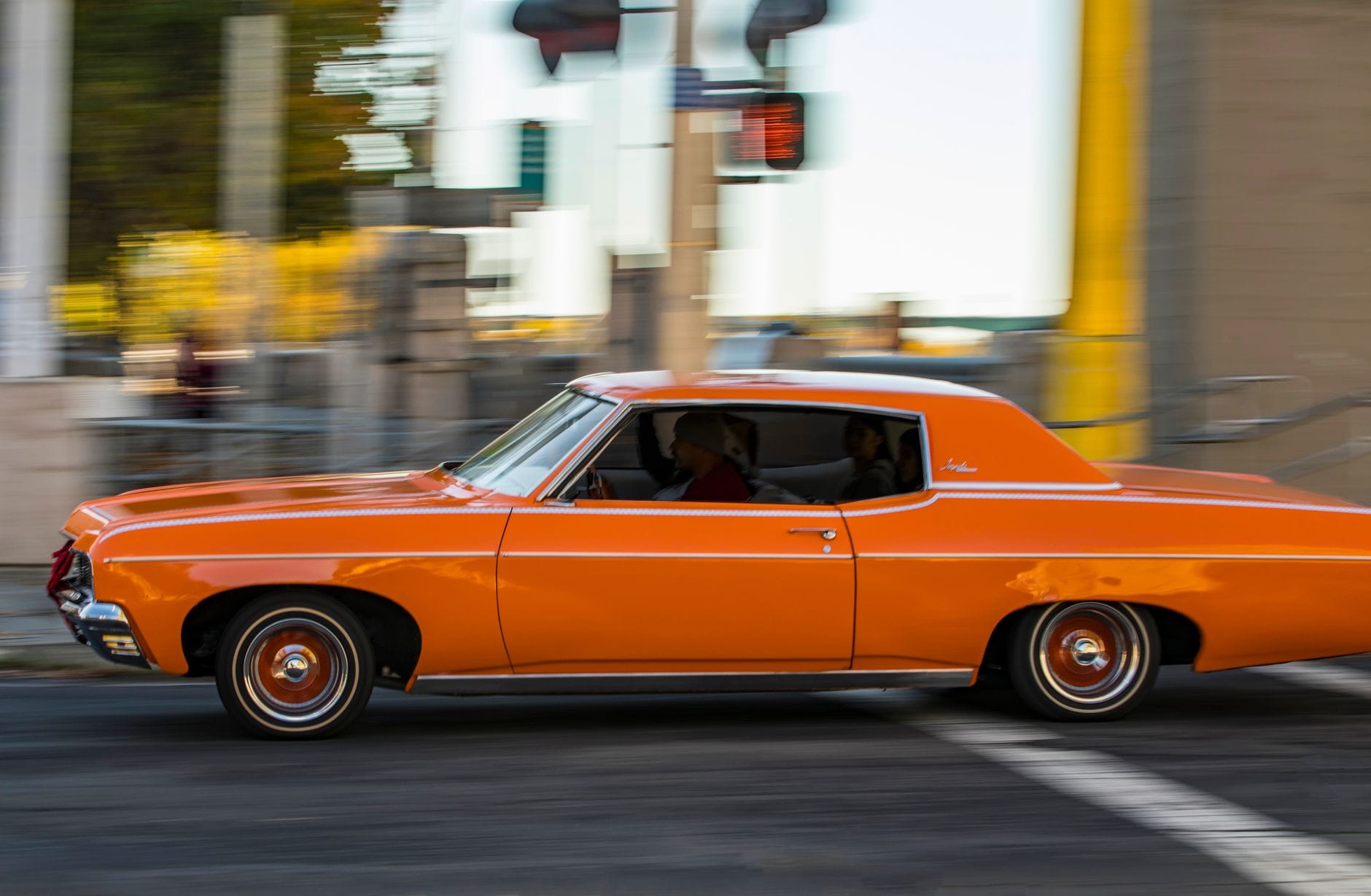 Pomarańczowy klasyczny samochód pędzący ulicami miasta