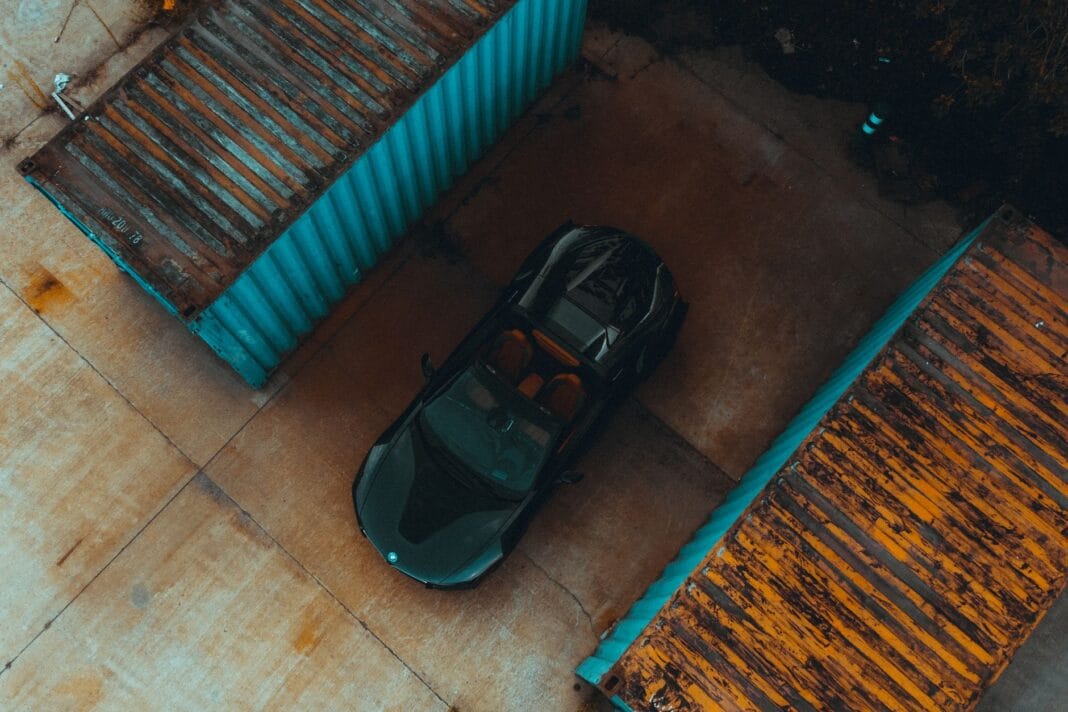 Czarny samochód sportowy między kolorowymi kontenerami transportowymi Czarny samochód sportowy między kolorowymi kontenerami transportowymi