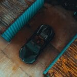 Czarny samochód sportowy między kolorowymi kontenerami transportowymi
