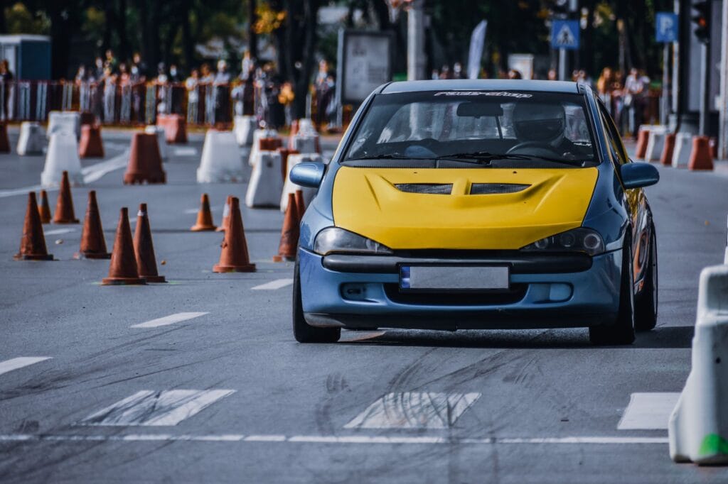 Kierowca żółtego Porsche jedzie miejską drogą między barierami