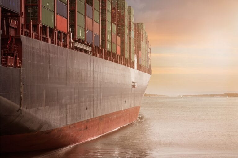 Kontenerowiec płynący o zachodzie słońca symbolizujący transport z USA